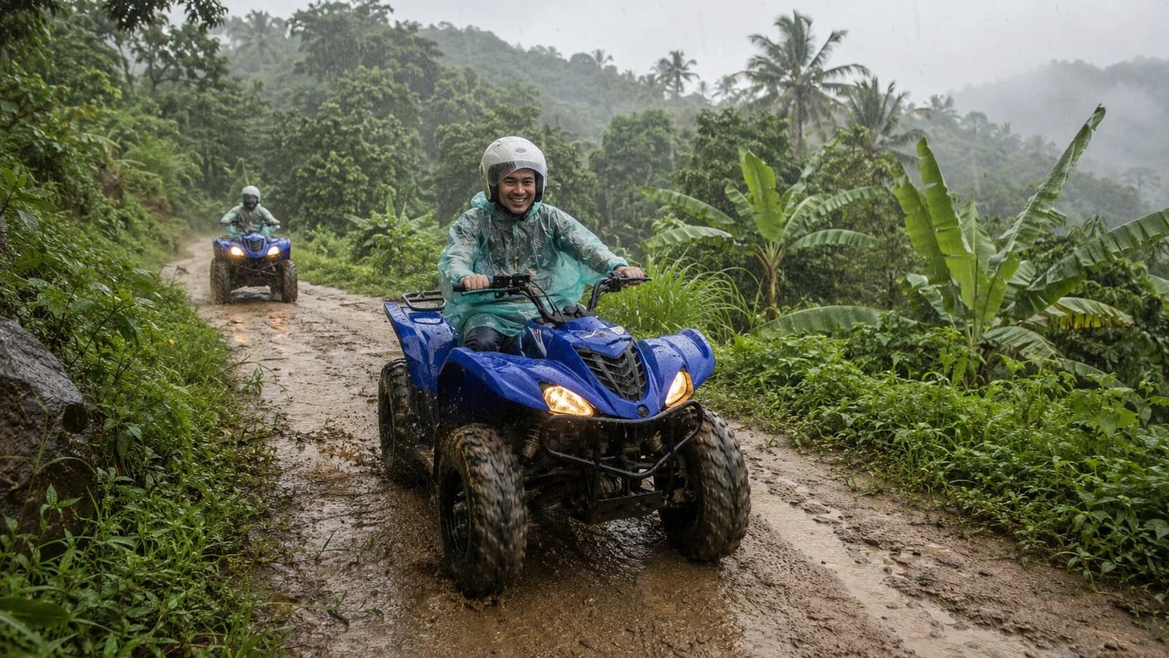 Two riders in rain ponchos on quad bikes on a muddy jungle trail in the rain, Koh Samui ATV tour in the wet season