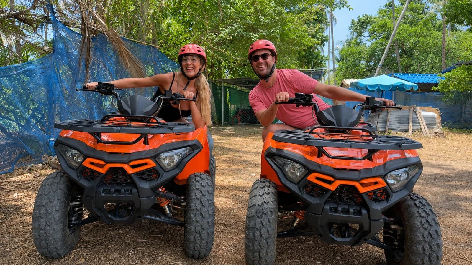 Couple in t-shirts, shorts and helmets on ATVs ready for a Koh Samui tour