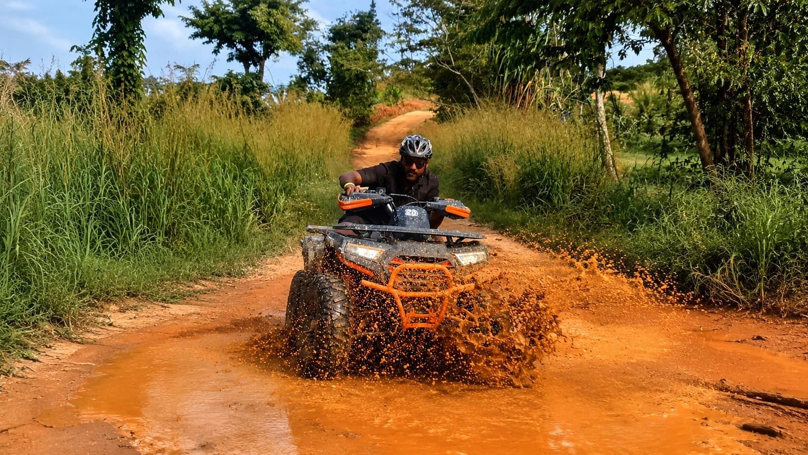 Rider in a helmet splashing through a muddy trail puddle on a Koh Samui ATV tour