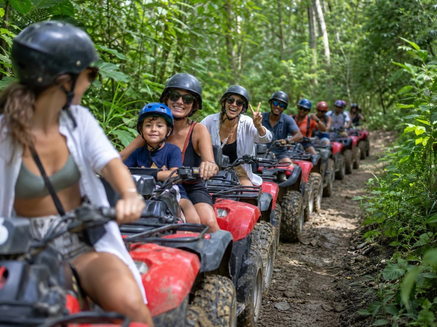 Family group on an ATV tour through the Koh Samui jungle, with a young child riding as a passenger